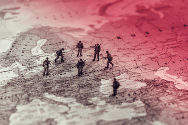 Miniature soldiers positioned on a map of Eastern Europe with a red gradient overlay.