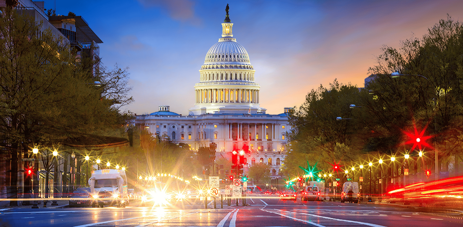 Capitol Building in Washington, DC at dusk with street lights and cars in the foreground