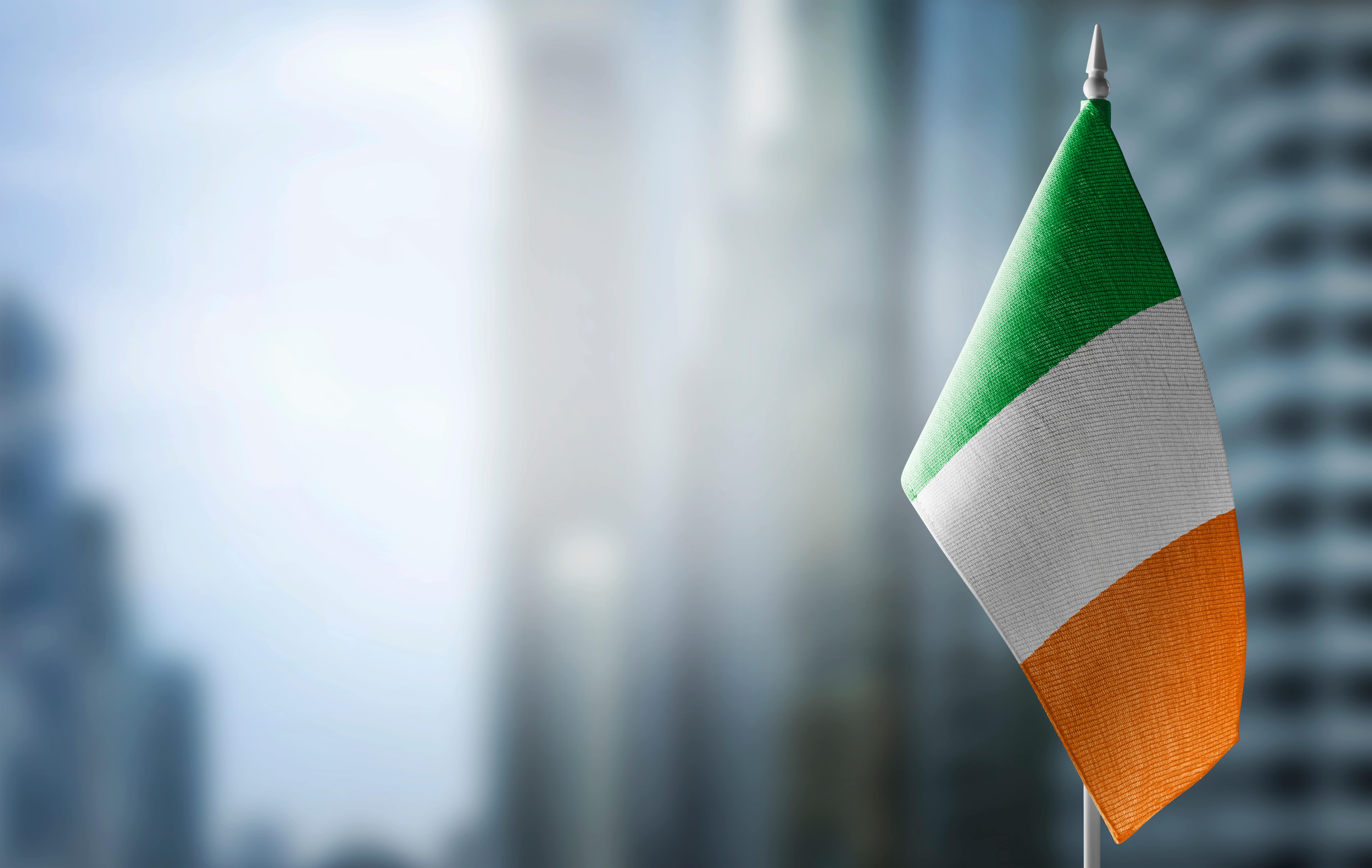 Irish flag waving with a blurred cityscape in the background.