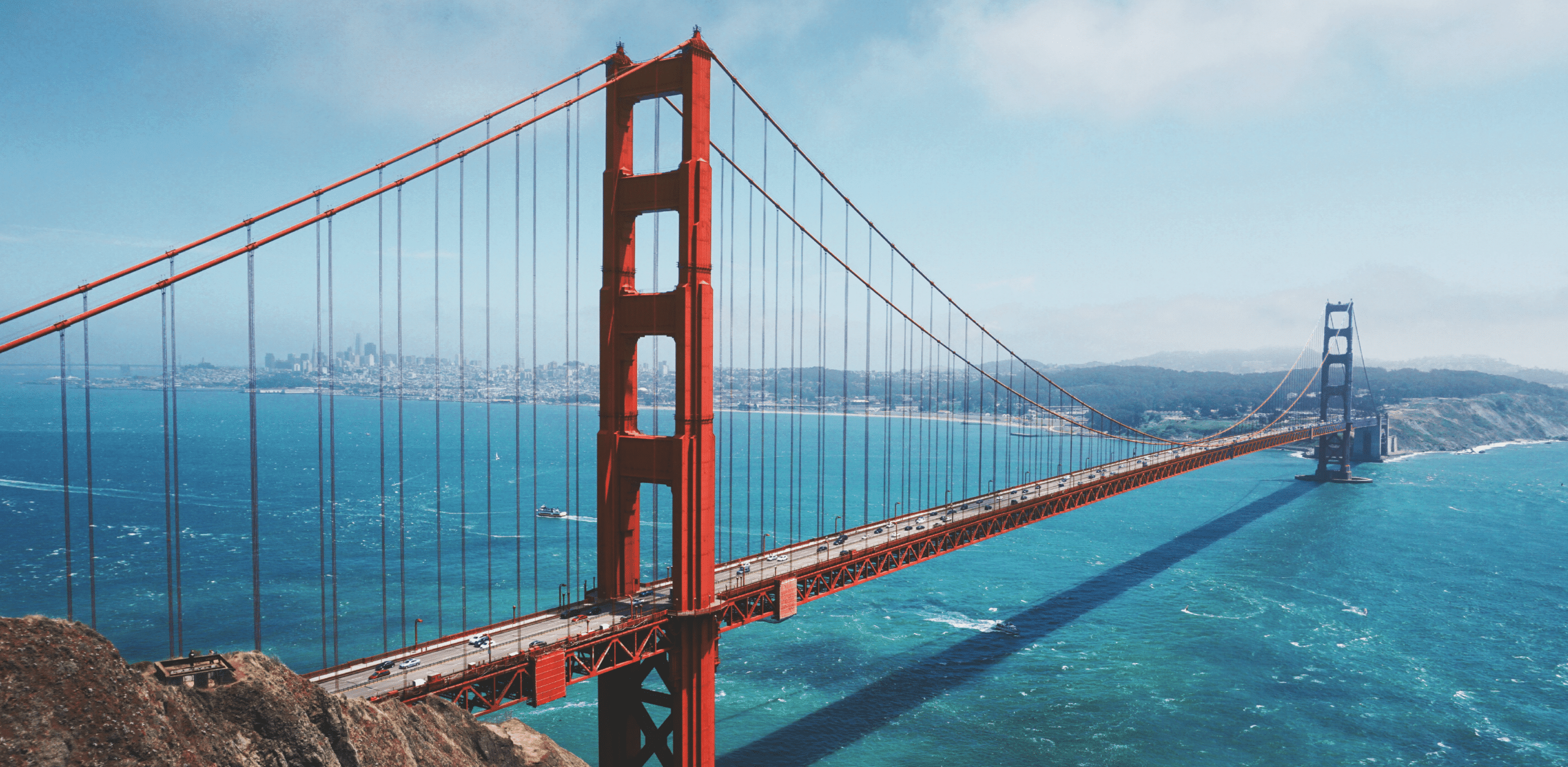 Golden Gate Bridge spanning over the San Francisco Bay with the city skyline in the background.