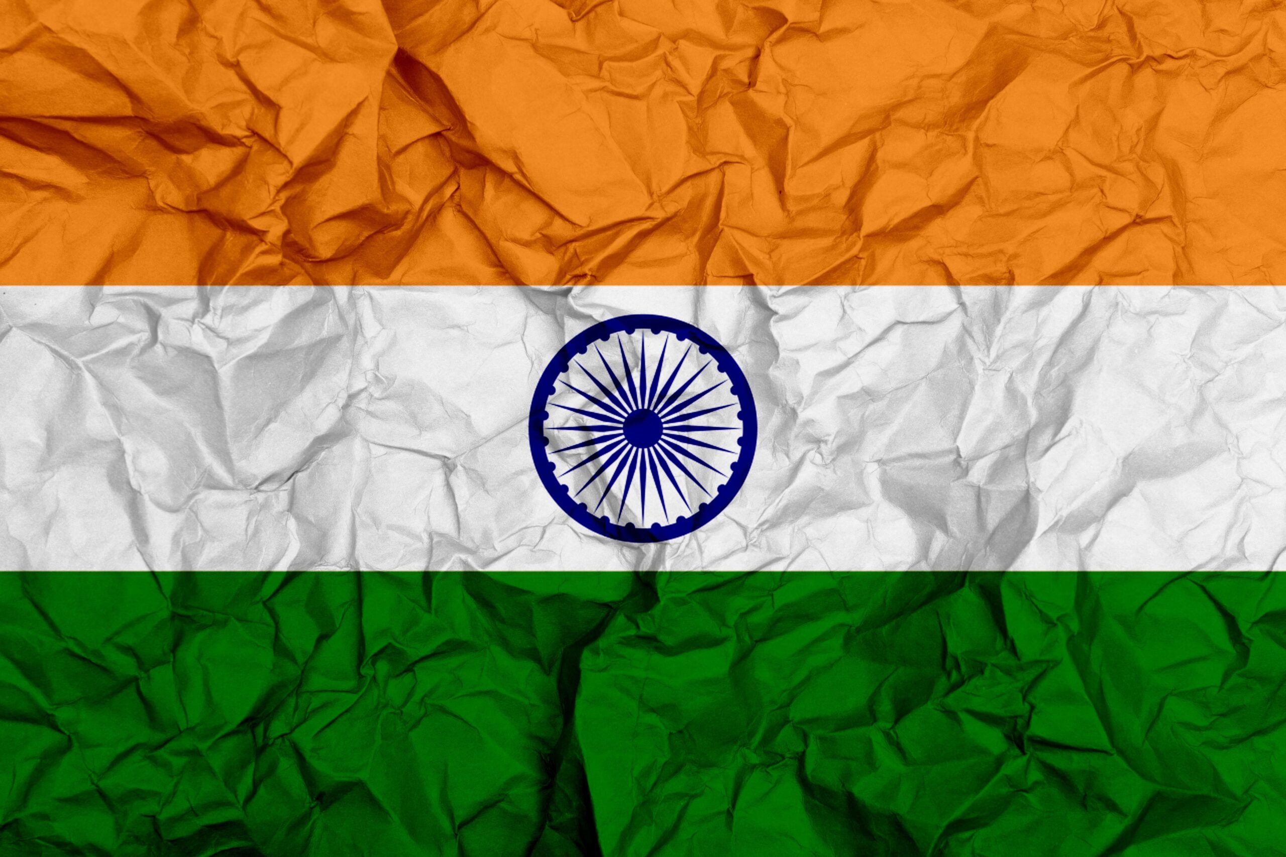 Crumpled Indian flag with orange, white, and green stripes and blue Ashoka Chakra.