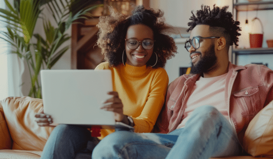 Smiling couple learning online together on a laptop at home.